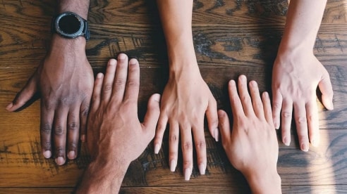 Five hands on a table